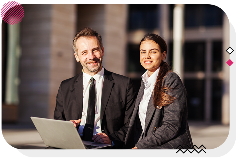 Man and woman holding a laptop and smiling at the camera