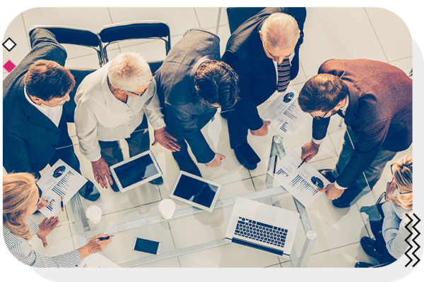 Group of people at a table standing and overlooking a mans notes