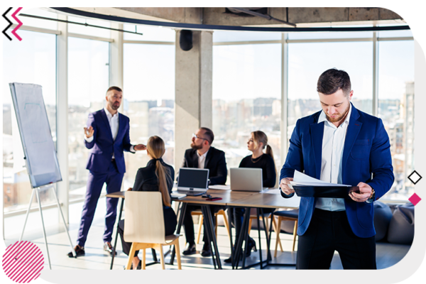 Man looking at notes while a presentation goes on behind him