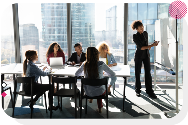 Group of people at a desk watching a woman present