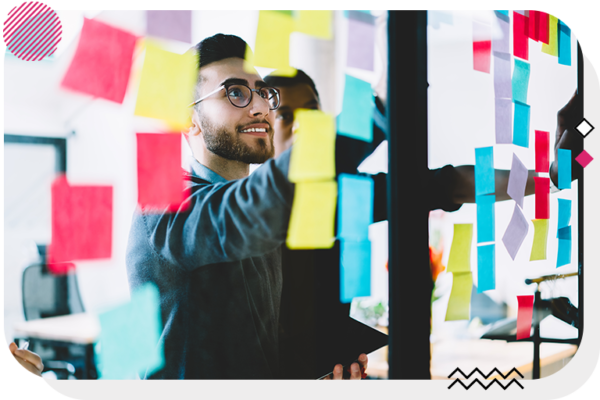 Man looking at a bunch of sticky notes on a wall