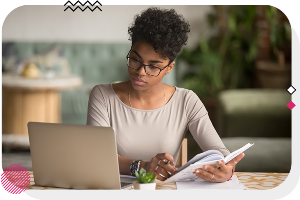 Woman looking at computer and flipping through notebook