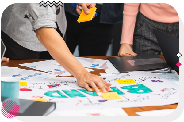 Group of 3 people putting sticky notes on a piece of paper