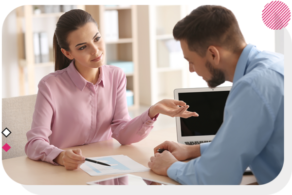 Woman showing man information on a piece of paper while they sit at a desk