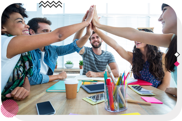 A group of people at a table all high fiving over the middle of the table