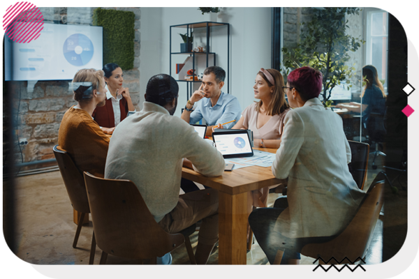 Group of people sitting around a table talking and watching a presentation