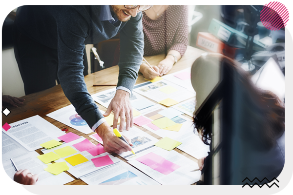 Man writing on sticky notes with a group of people at a desk