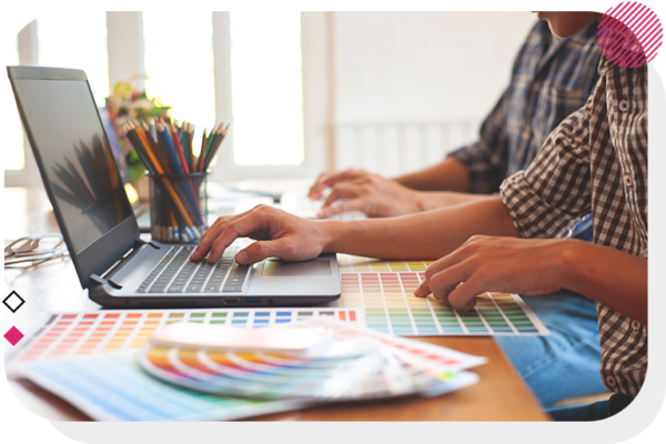 Person on a computer with a bunch of colour swatch papers around them