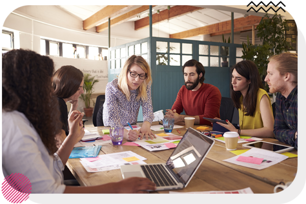 Group of people around a table and looking at notes in the middle of the table